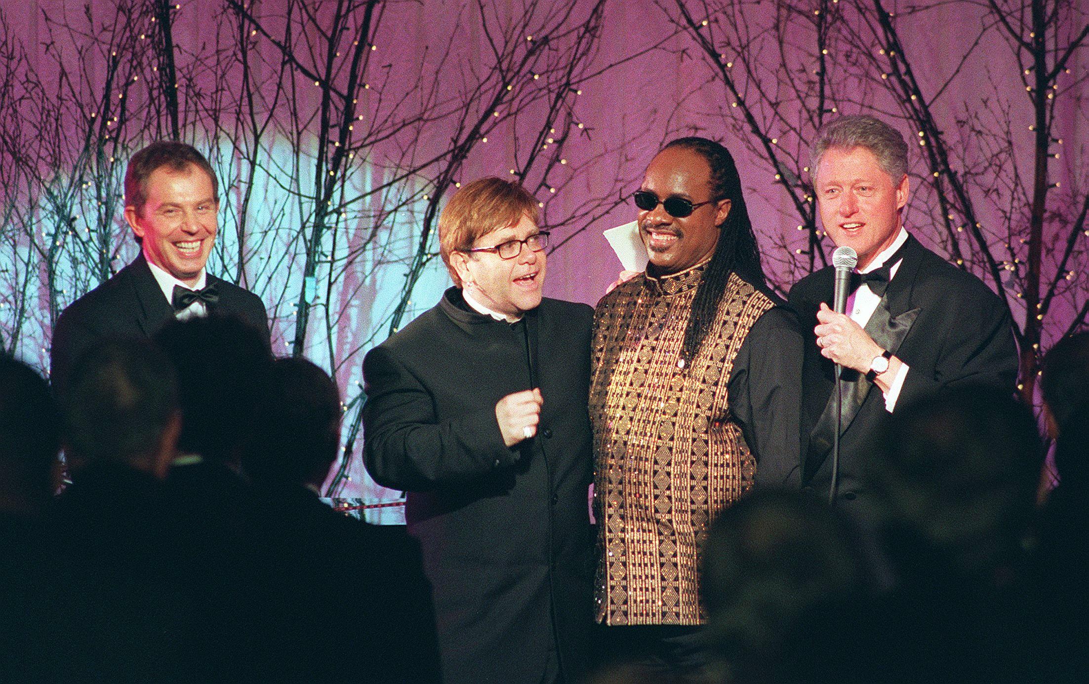 Febbraio 1997. In good company: Elton John partecipa alla cena di stato in onore del primo ministro inglese Tony Blair alla Casa Bianca. Da sinistra a destra: Tony Blair, Elton John, Stevie Wonder e Bill Clinton