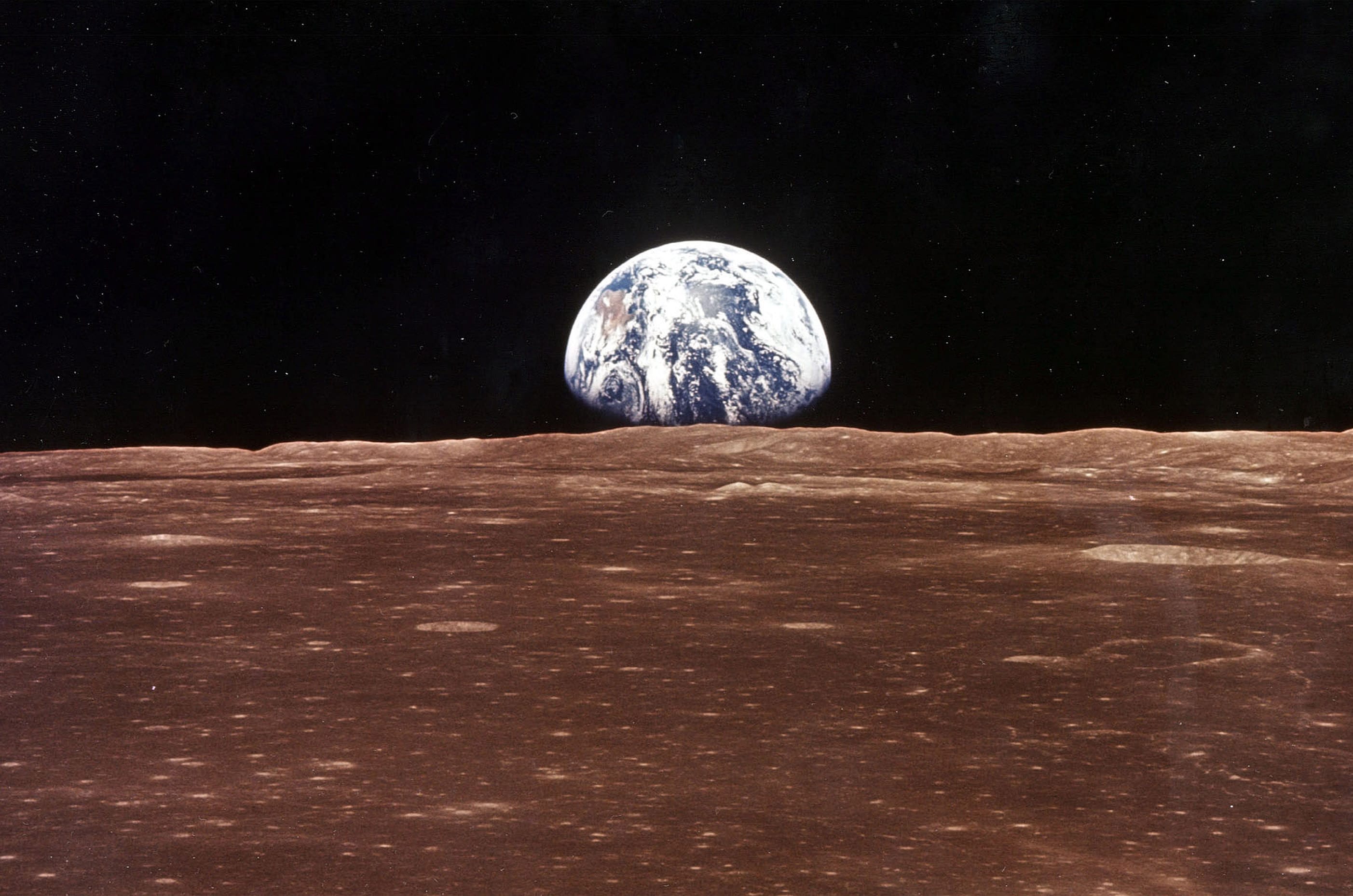 LA Terra appare sull'orizzonte lunare mentre il Modulo di Comando dell'Apollo 11 entra in vista della Luna.