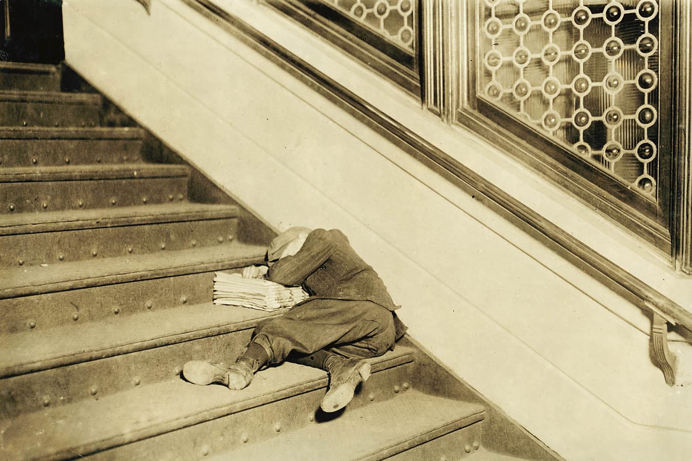Strillone addormentato sulle scale con i suoi giornali. Novembre 1912. Jersey City, New Jersey, USA. Foto di Lewis Wickes Hine. © Courtesy Library of Congress, Prints & Photographs Division, National Child Labor Committee Collection