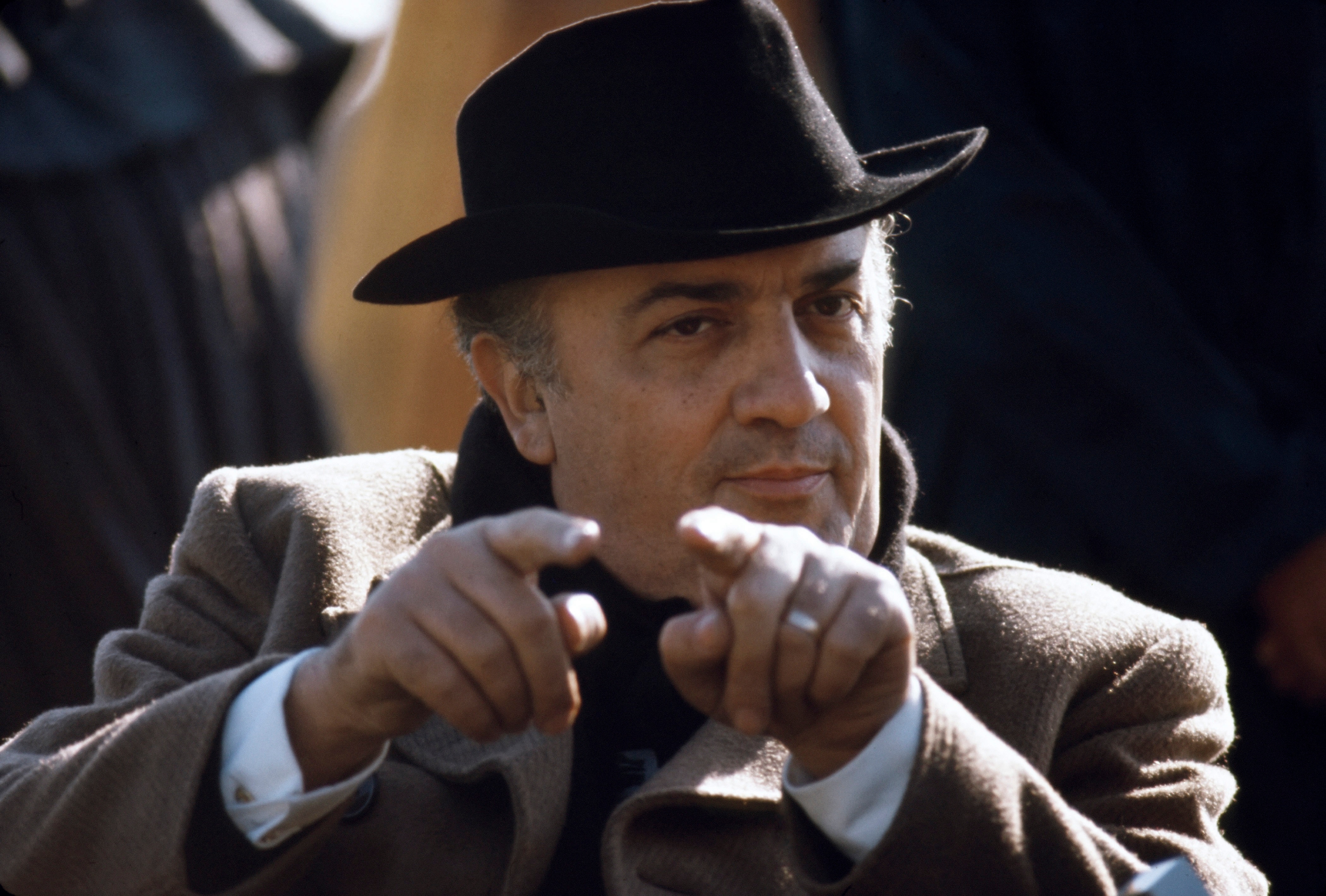 Seduto sulla sua sedia da regista, cappello in testa