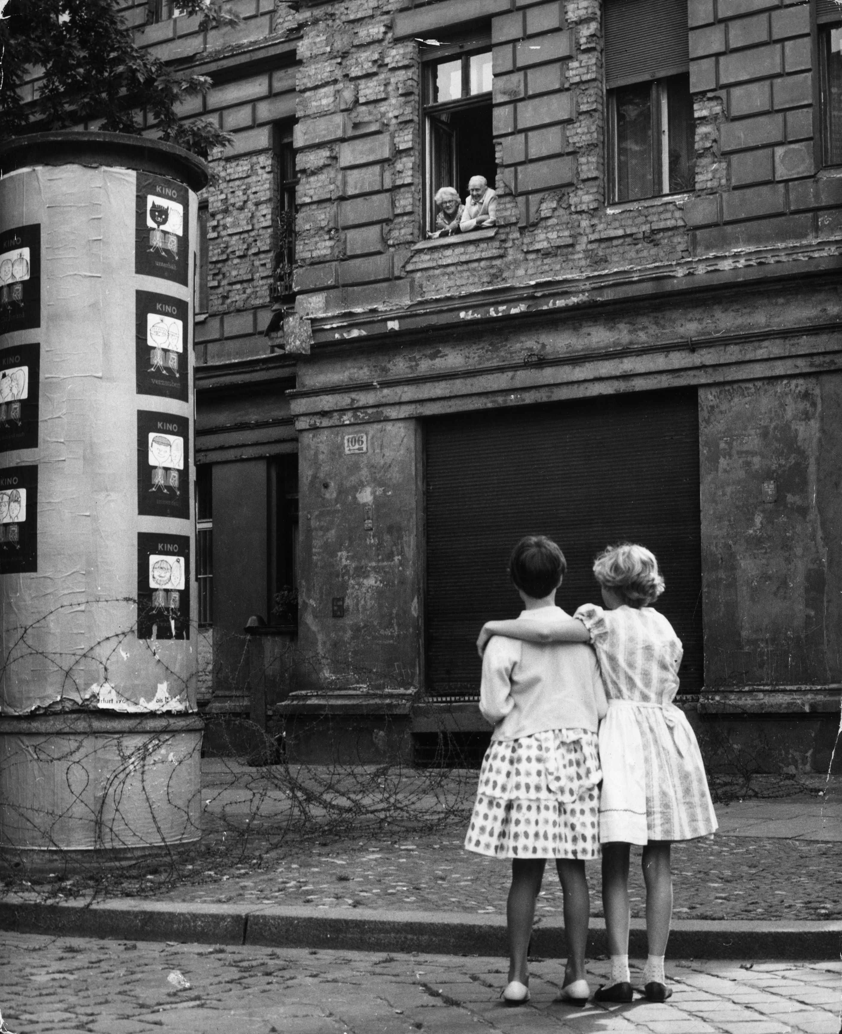 Il 14 agosto 1961, pochi giorni dopo la costruzione del muro, due bambine in una strada della parte occidentale parlano con i nonni che si trovano alla finestra di casa loro nel settore orientale. Vengono divisi palazzi, scuole e addirittura cimiteri. Numerose famiglie si trovano spaccate tra le due parti della città