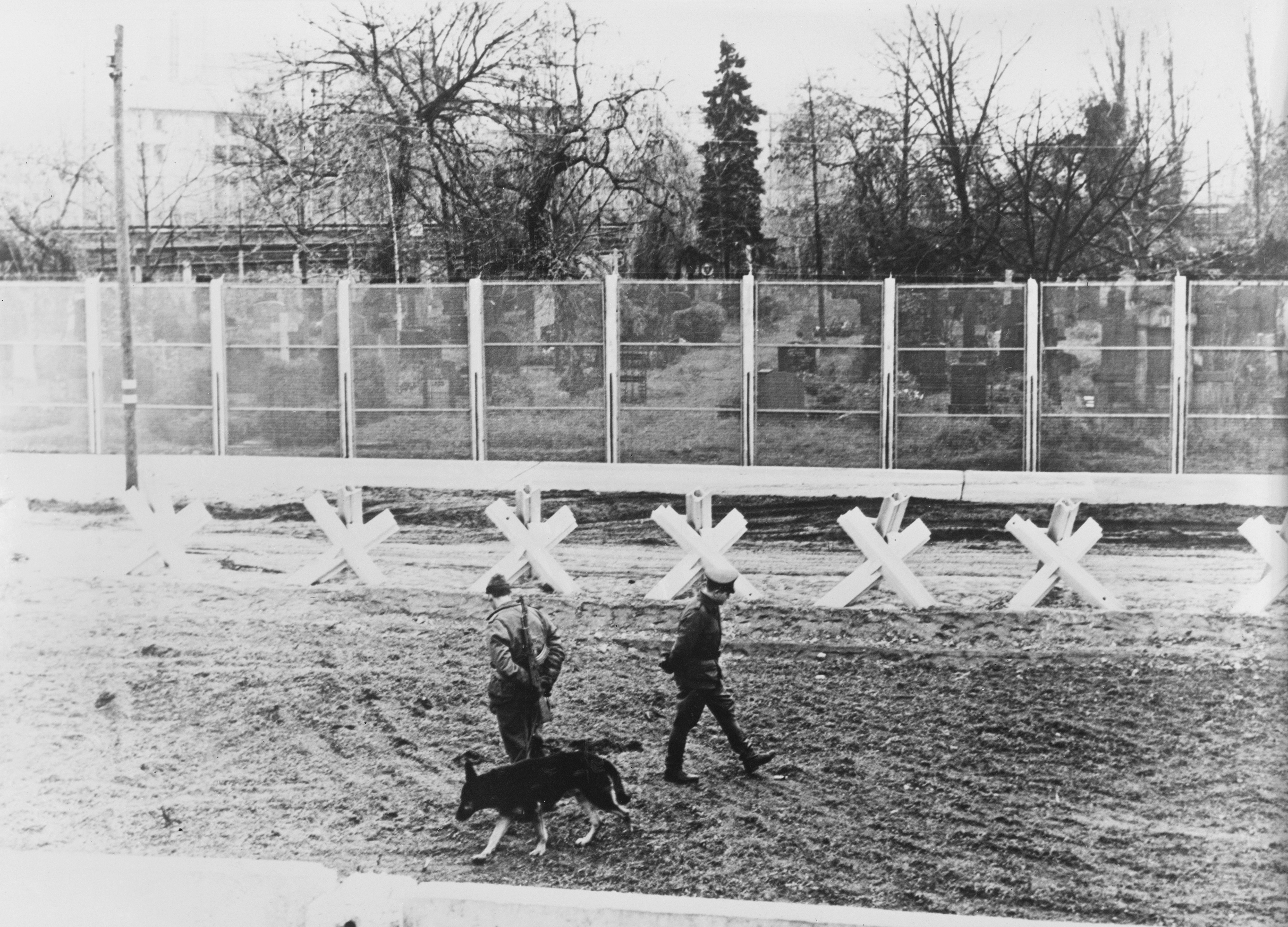 Guardie di frontiera della Germania Orientale, nel 1967, sorvegliano con i cani la cosiddetta “striscia della morte”, lo spazio che intercorre tra i due muri costruiti a distanza di 10 metri circa. Le guardie hanno l’ordine di sparare a chiunque si trovi all’interno di questa area
