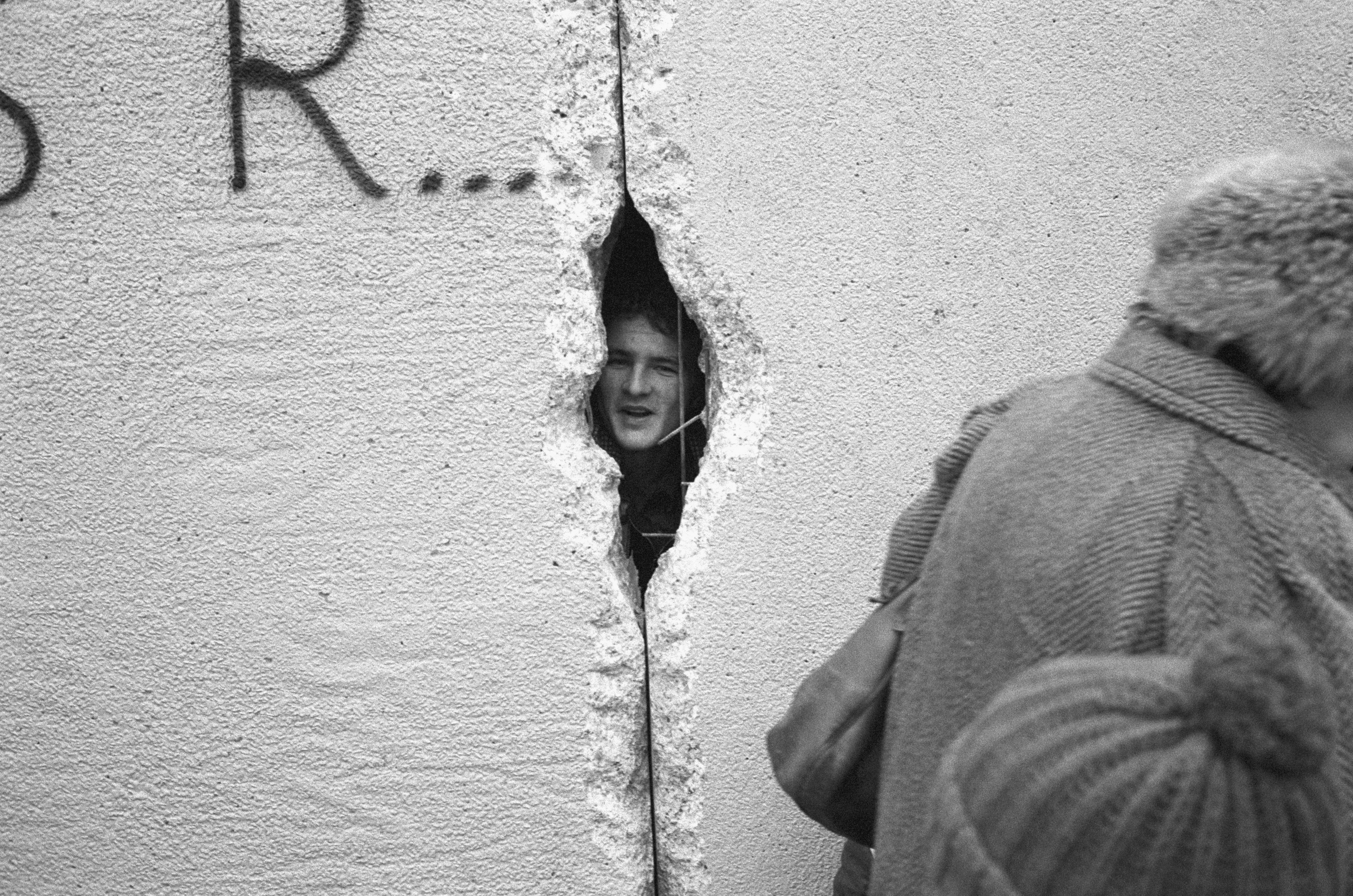 Un giovane guarda Berlino Est attraverso uno squarcio realizzato sul muro, il 31 dicembre 1989