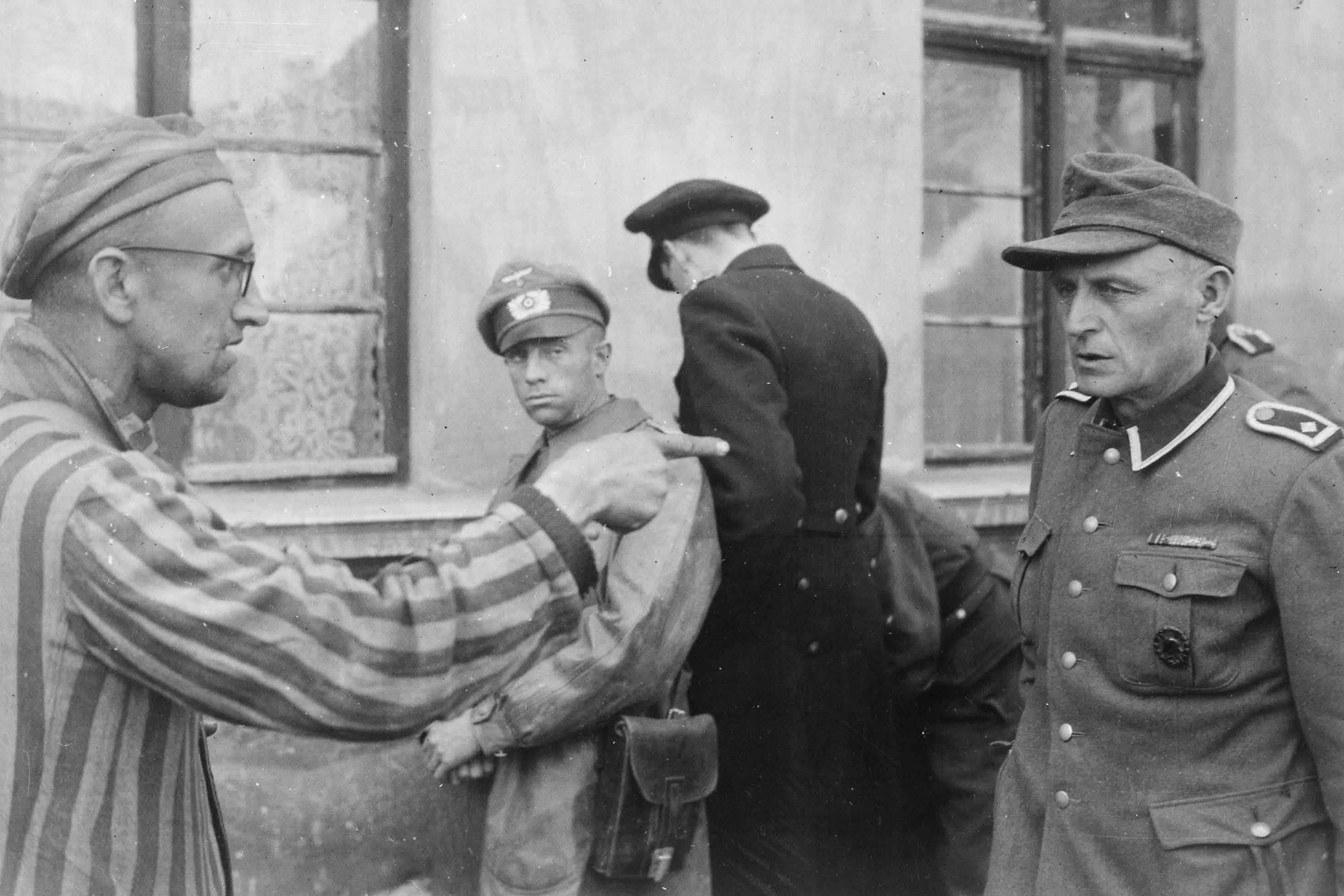 14 maggio 1945. Un lavoratore russo tra i prigionieri liberati dalla 3a Divisione Corazzata indica una ex guardia nazista che picchiava brutalmente i prigionieri. Germania. Autore sconosciuto. © courtesy U.S. National Archives and Records Administration