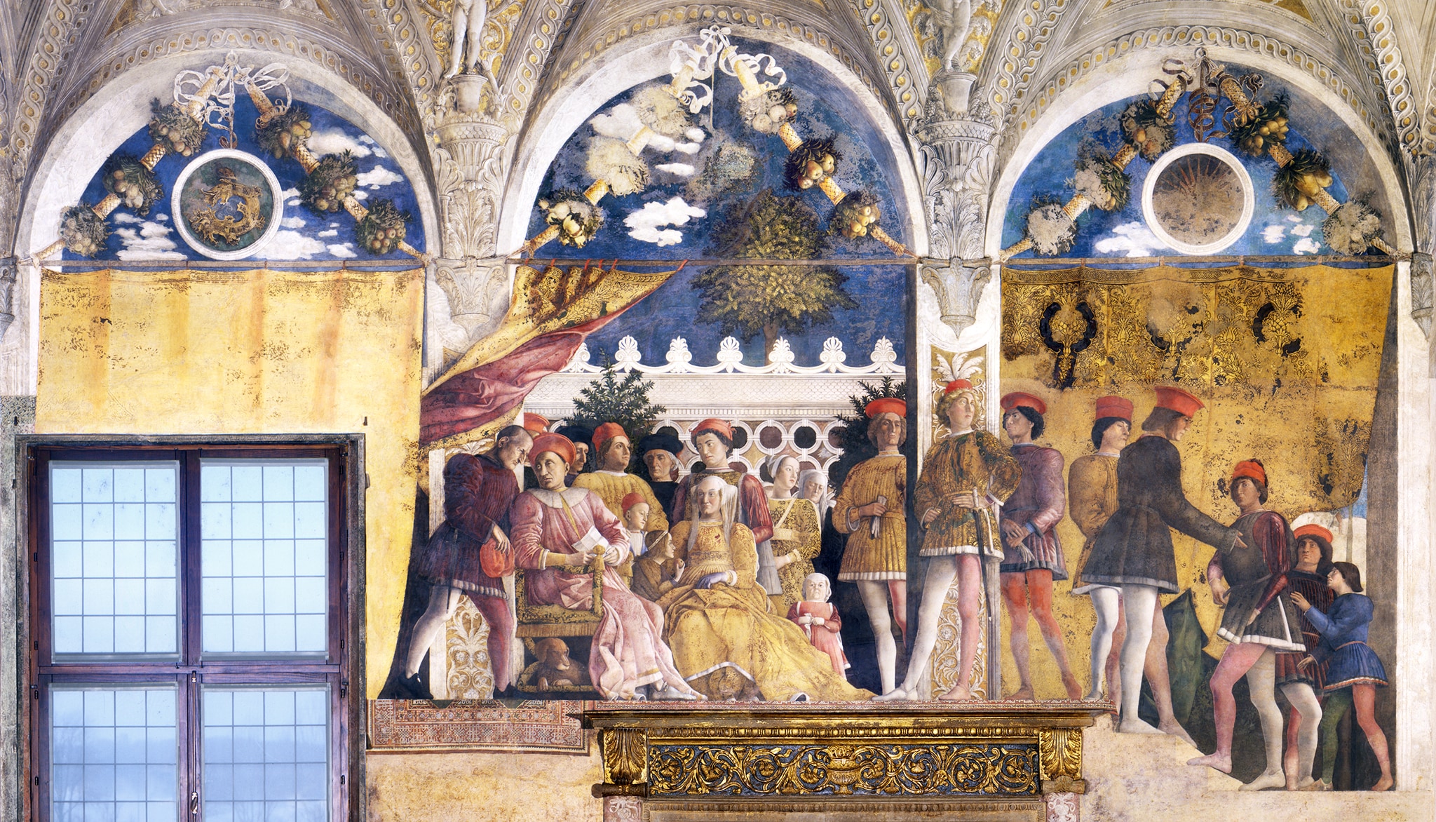 La corte riunita, Camera degli Sposi, Andrea Mantegna. Sulla parete ovest, la corte Gonzaga è rappresentata in modo informale, sorpresa nel momento in cui un messaggero consegna una lettera a Ludovico, affiancato dalla moglie Barbara di Brandeburgo. Alla prodigiosa galleria di ritratti, si aggiunge l'originale espediente di adattare la scena al camino sottostante usato come piattaforma rialzata.