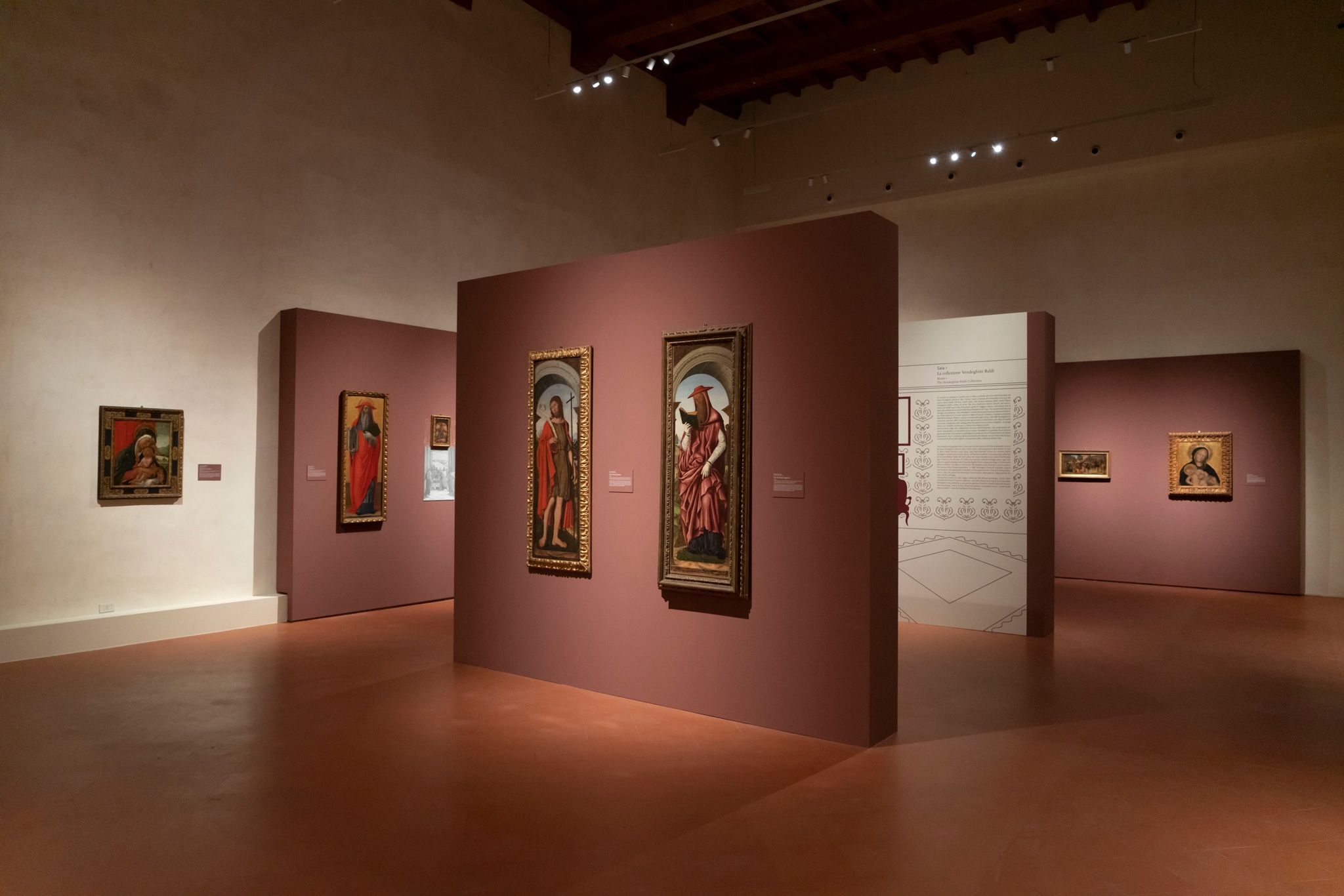 Sala 1. Sala della collezione Vendeghini Baldi, donata alla Pinacoteca nel 1973. Al centro sono visibili due tavole di polittico di ignoto pittore ferrarese di fine '400, raffiguranti San Giovanni Battista e San Girolamo (quest’ultima giunta in museo già nel 1846). Sullo sfondo a destra la Madonna col Bambino di Gentile da Fabriano.