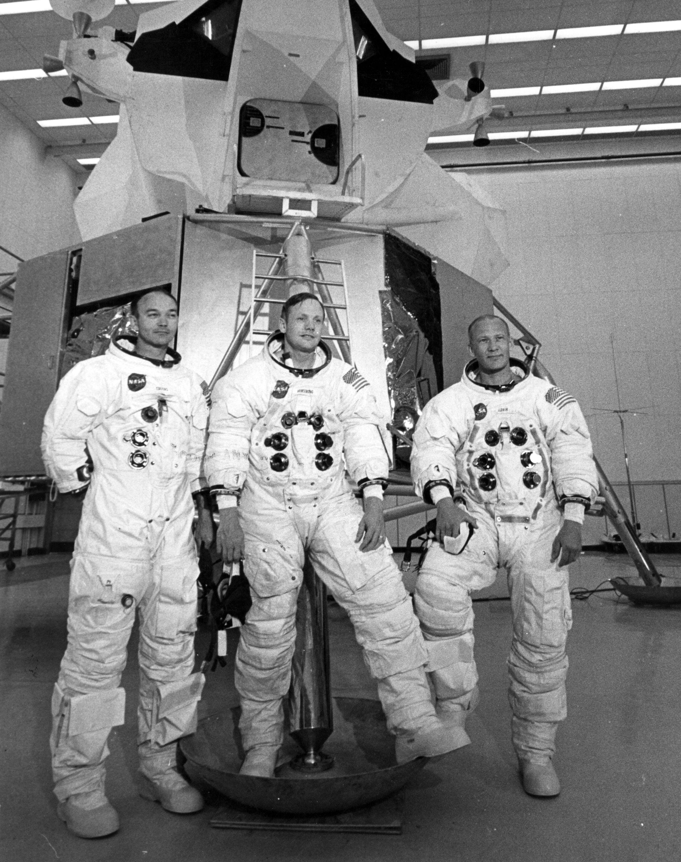 I tre astronauti con le tute posano davanti al simulatore del modulo di atterraggio lunare al Kennedy Space Center