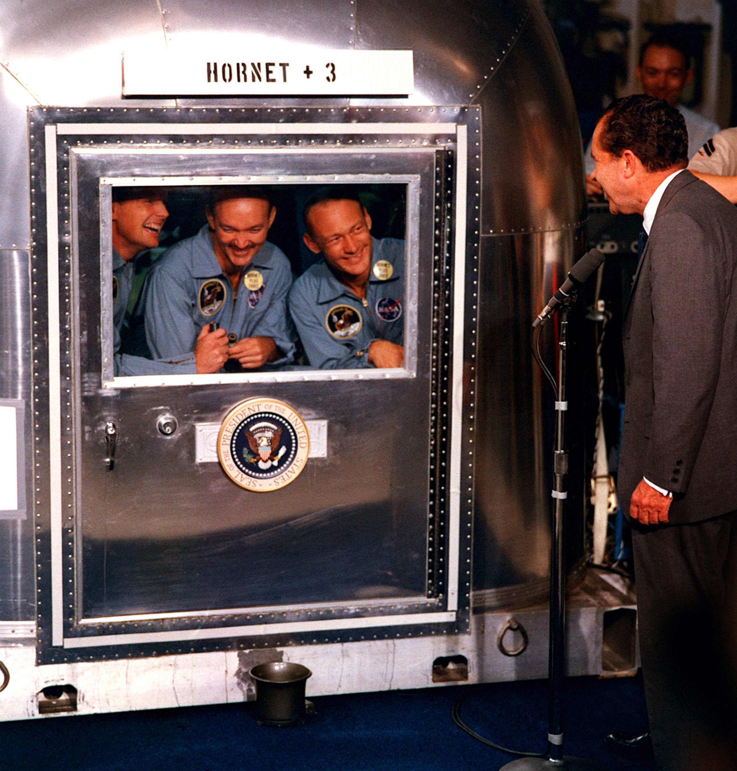 Il Presidente Nixon saluta i tre astronauti in isolamento cautelativo dopo il ritorno dal viaggio lunare