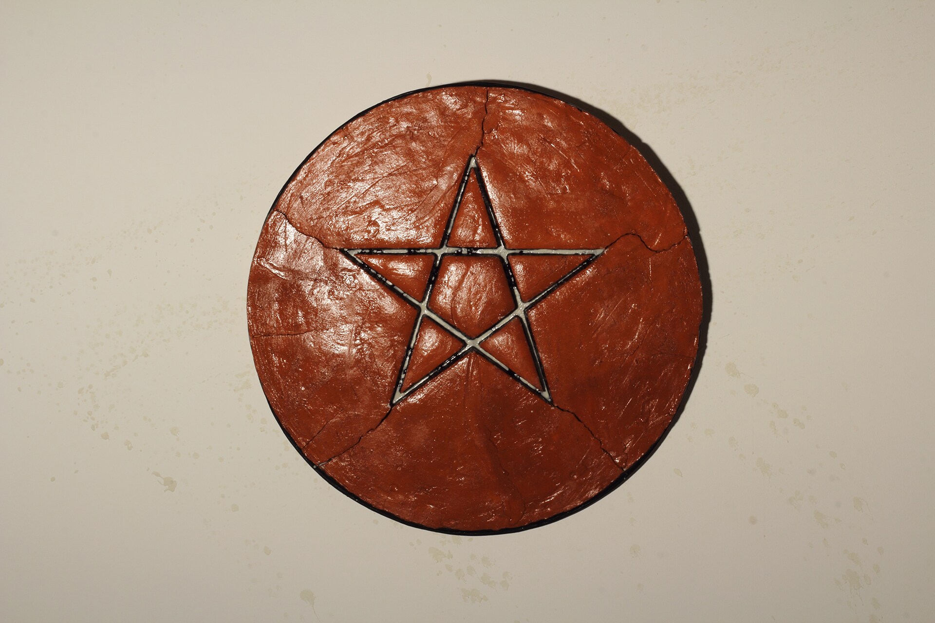 Gilberto Zorio "Stella di terracotta con memoria", 2020-21. Terracotta, fosforo, legno, lampada, cavalletto portalampada. Diametro 97,5 x 12 cm 