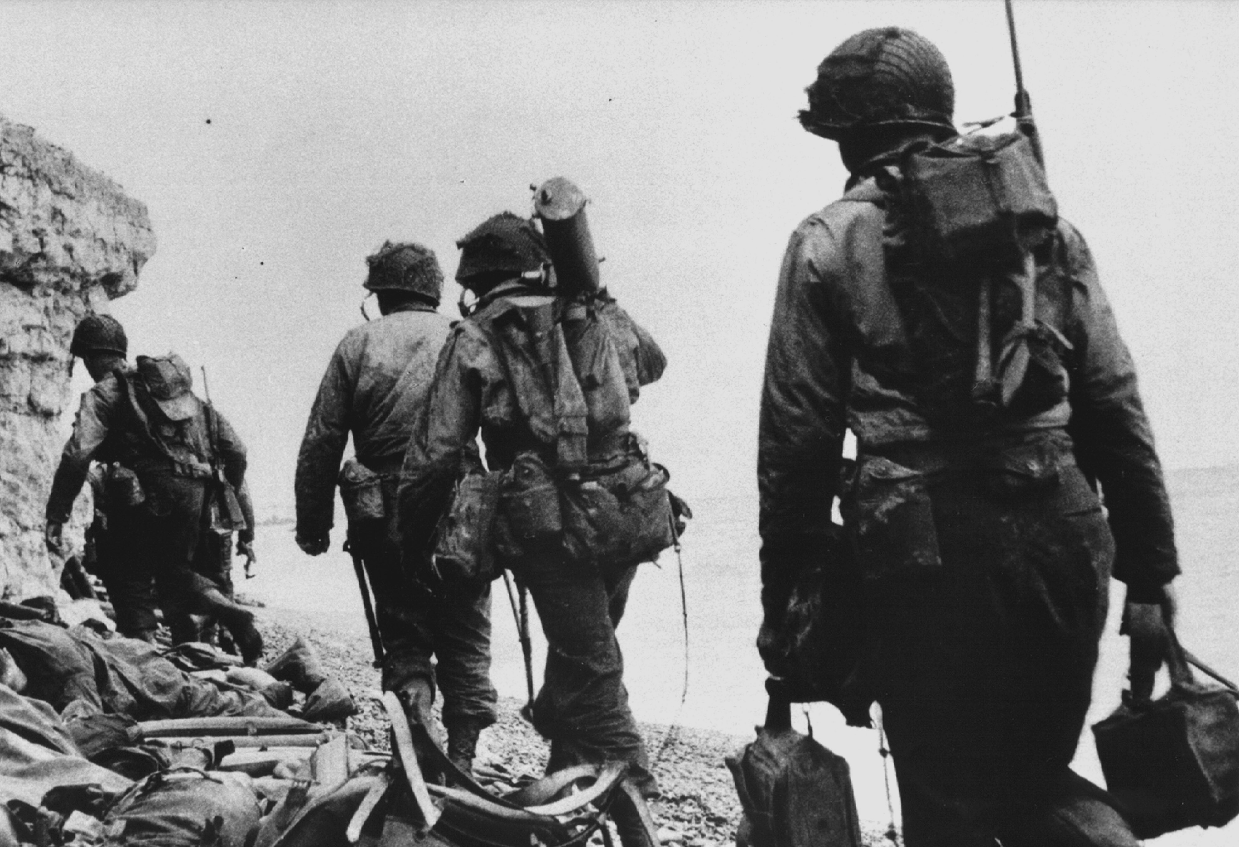 Sotto il Wn 60, ai piedi della scogliera di Colleville sur Mer, una squadra di HMG (Heavy Machin Guns) lascia la spiaggia: deve trovare un riparo prima di attaccare la postazione del Wn 60”. Il secondo soldato da destra porta a tracolla una mitragliatrice Browning raffreddata ad acqua. 6 giugno 1944, spiaggia di Omaha, Normandia, Francia. Fotografo: sconosciuto o non fornito Per gentile concessione di Photos Normandie / U.S. National Archives 