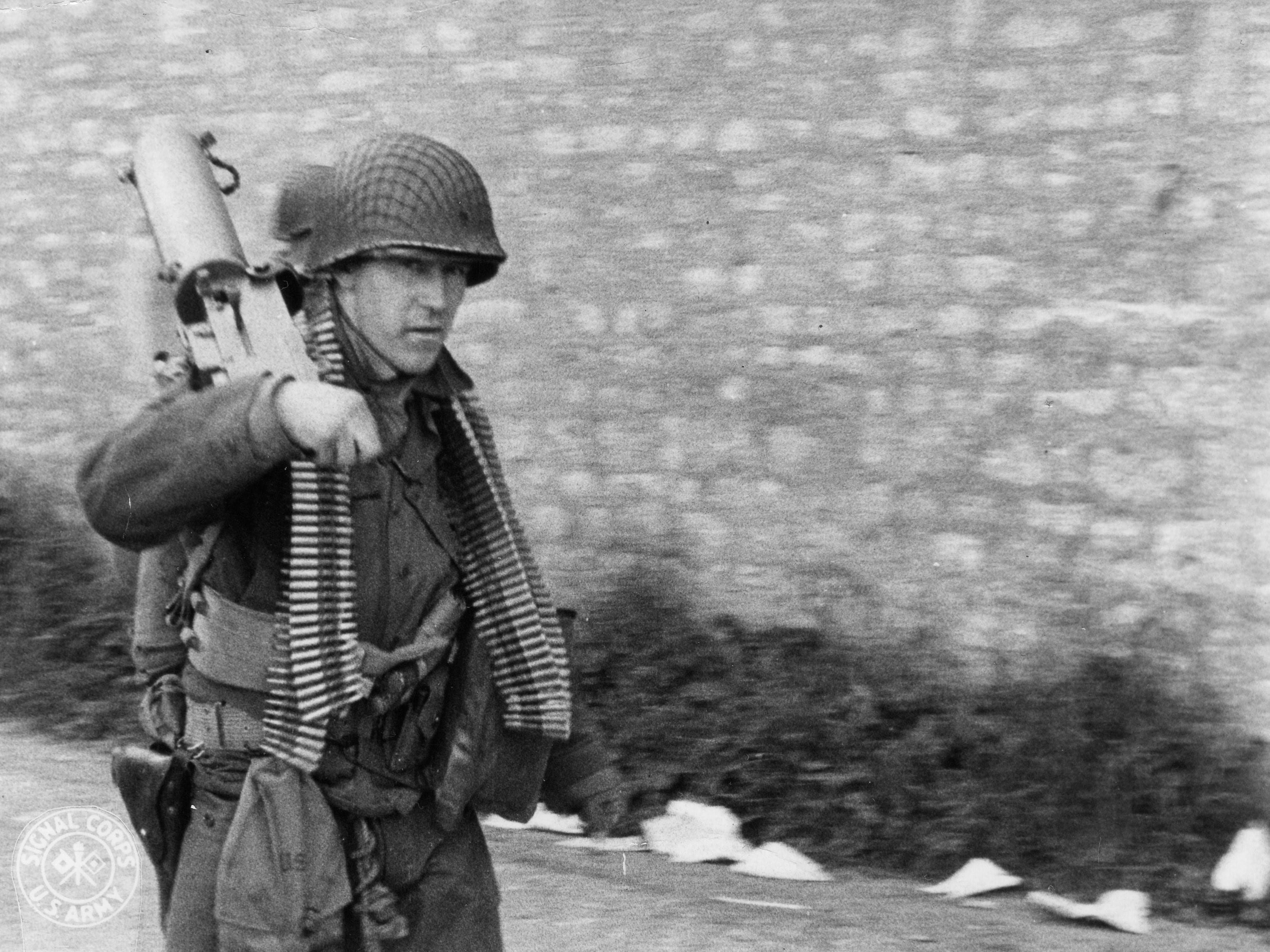 Questo determinato soldato americano, con la mitragliatrice a tracolla e le munizioni al collo, si muove lungo una strada nel nord della Francia per sostenere l'avanzata delle truppe dell'8° reggimento di fanteria, 4° divisione di fanteria. 9 giugno 1944, Normandia, Francia. Fotografo: Shelton Per gentile concessione degli U.S. National Archives Digitalizzato da Signal Corps Archive 